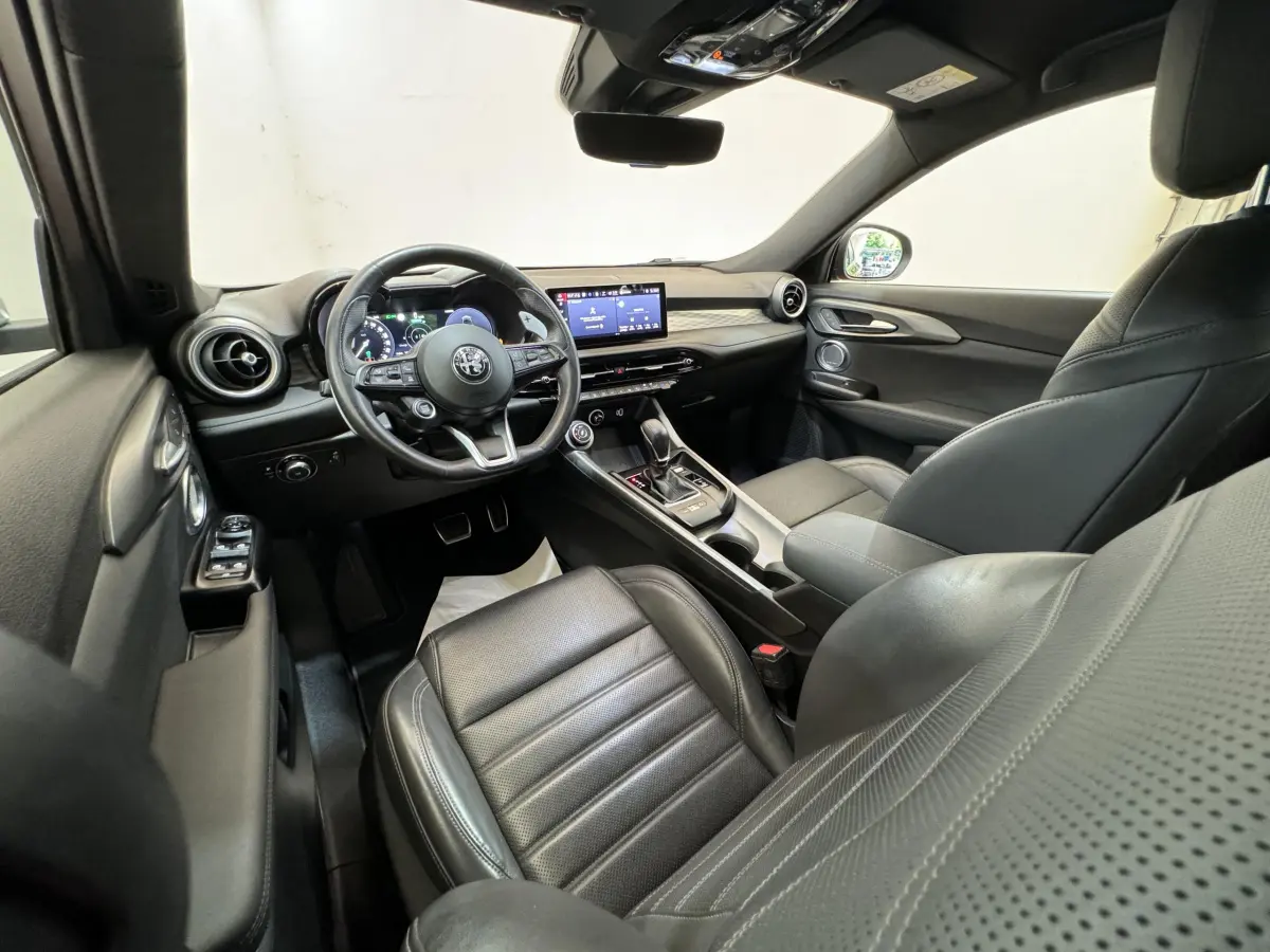 Intérieur noir de l'Alfa Romeo Tonale 2023, vue côté conducteur, volant cuir et écran tactile central visible.