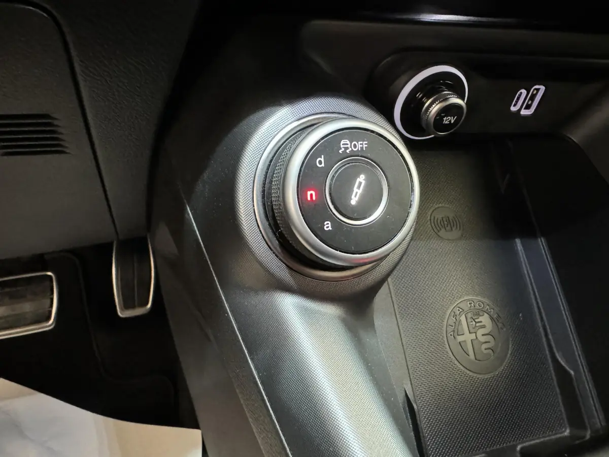 Gros plan sur la molette de sélection de boîte auto et prise 12V dans l'habitacle noir de l'Alfa Romeo Tonale rouge 2023.