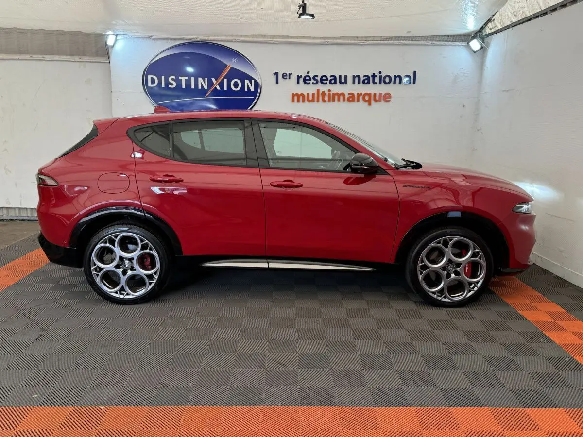 Profil droit de l'Alfa Romeo Tonale rouge 2023 avec jantes spécifiques et logo Edizione Speciale visible sur l'aile avant.