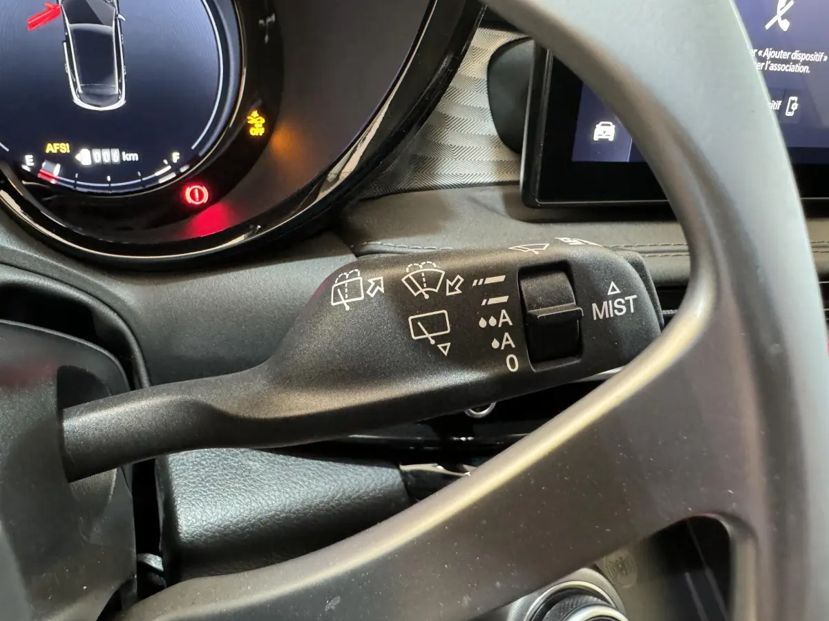 Gros plan sur la manette d’essuie-glace noire et le tableau de bord numérique de l’Alfa Romeo Tonale rouge 2023.