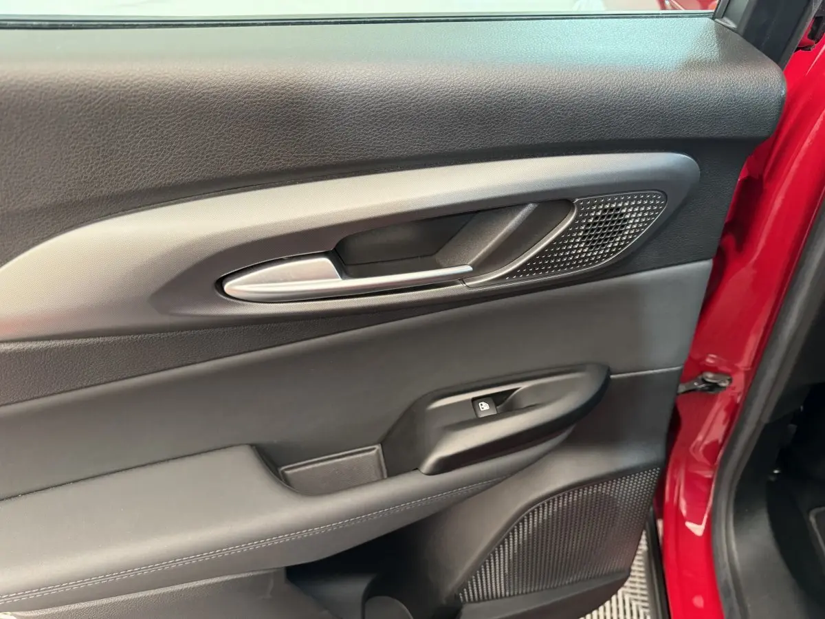 Détail de la porte côté gauche intérieure noire avec poignée alu et partie extérieure rouge visible d'une Alfa Romeo Tonale 2023.