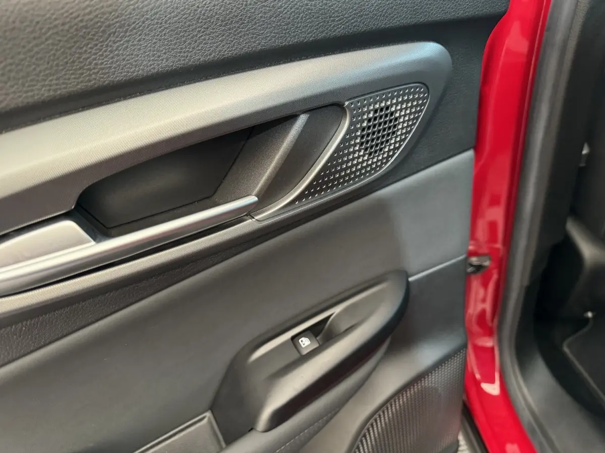 Gros plan sur la porte côté gauche rouge de l'Alfa Romeo Tonale 2023, avec poignée et commande de vitre noire.