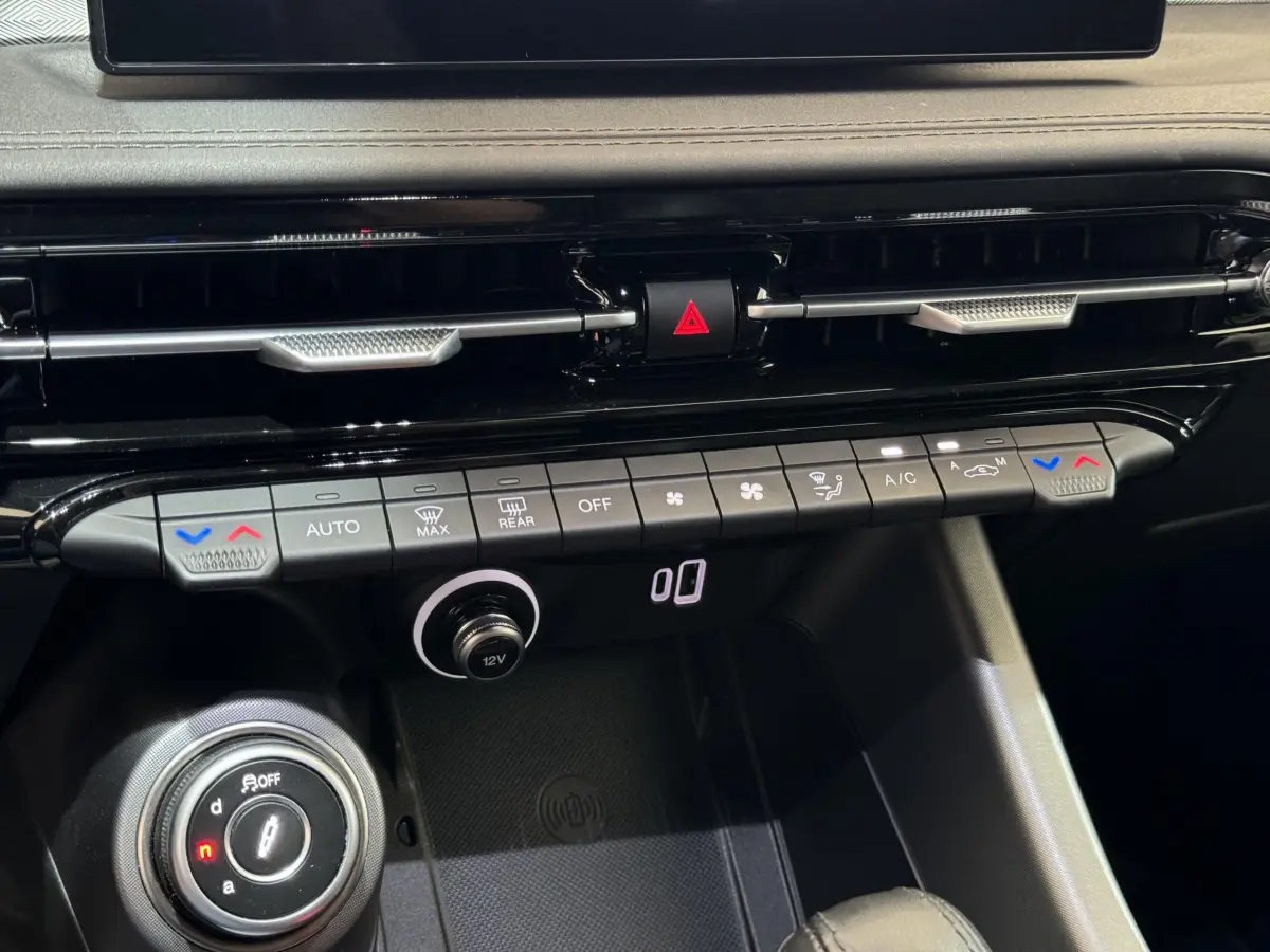 Vue rapprochée du tableau de bord noir de l'Alfa Romeo Tonale rouge, montrant les commandes de climatisation et la molette de sélection.