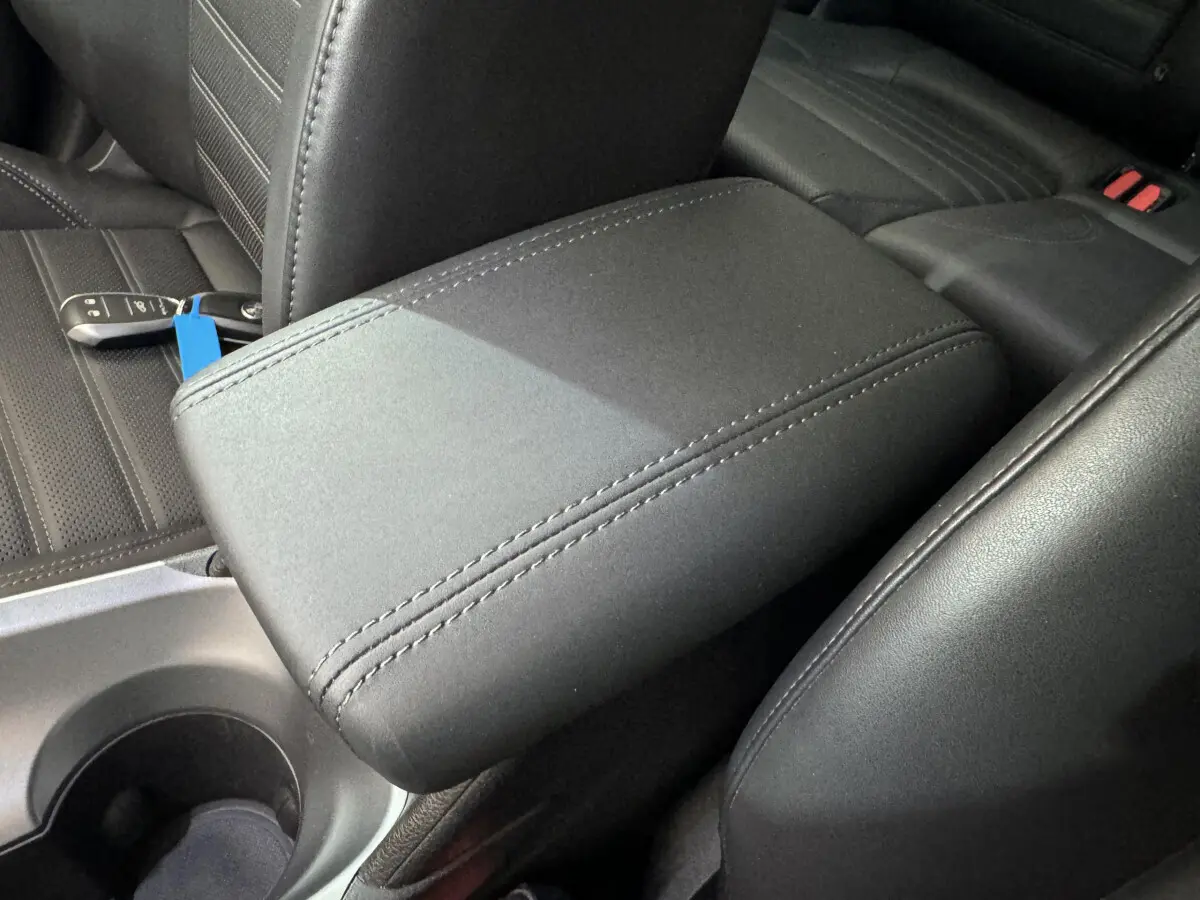 Accoudoir central en tissu noir avec coutures apparentes, siège arrière et clé Alfa Romeo Tonale visible en arrière-plan.