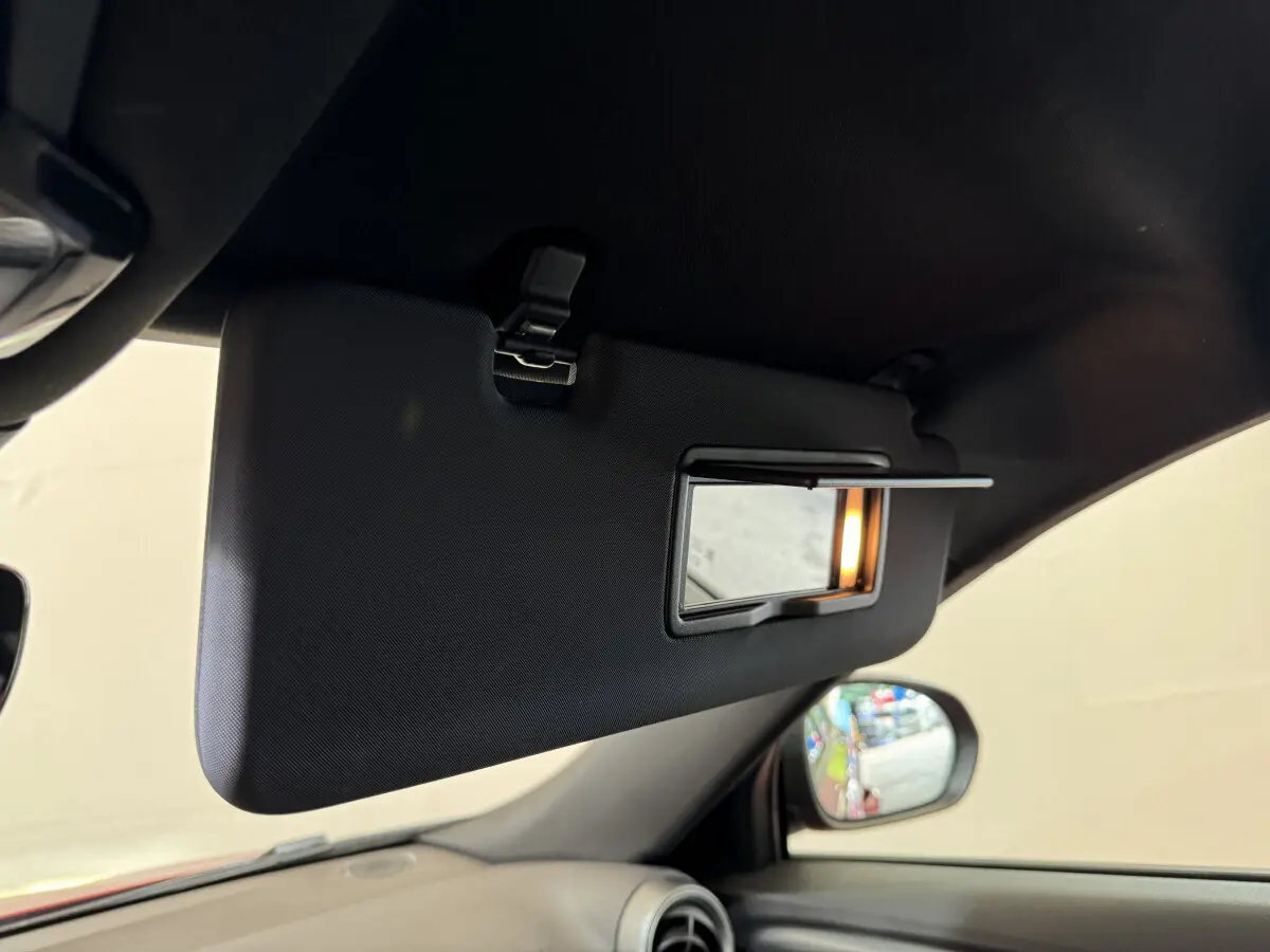 Détail du pare-soleil côté conducteur avec miroir éclairé dans l'habitacle rouge de l'Alfa Romeo Tonale 2023