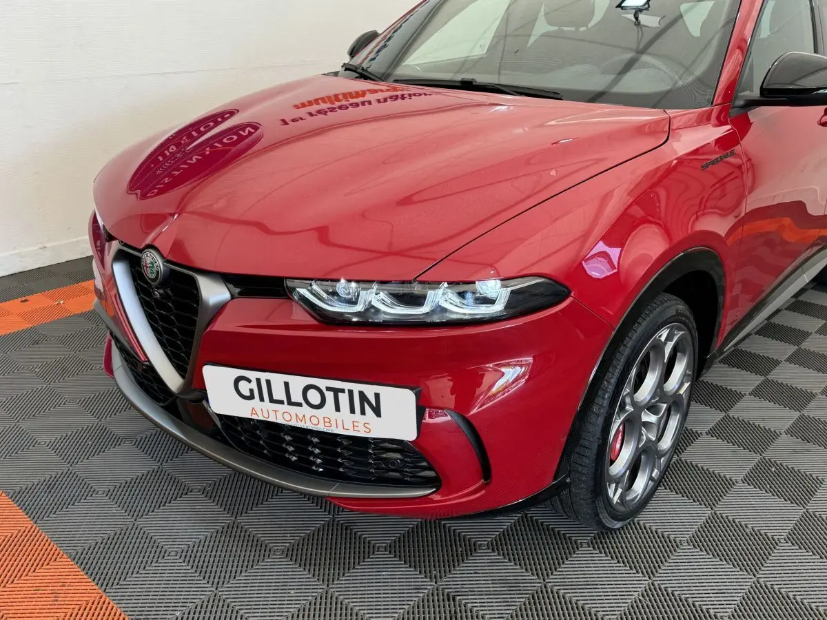 Vue 3/4 avant droit d'une Alfa Romeo Tonale rouge avec calandre caractéristique et jantes alu spécifiques Edizione Speciale.