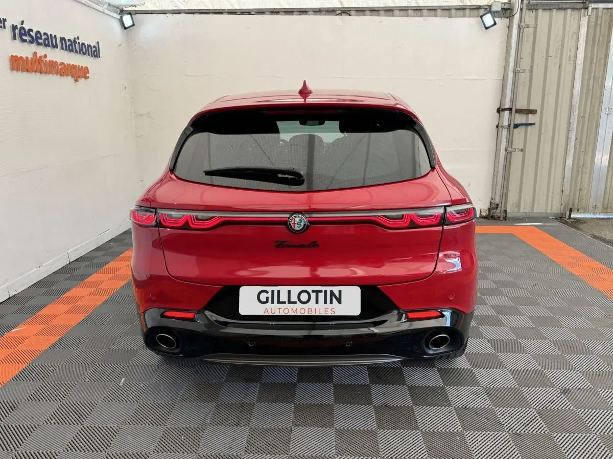 Vue arrière d'une Alfa Romeo Tonale rouge 2023 avec feux LED reliés et double sortie d'échappement noire.