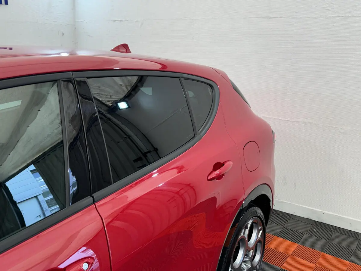 Vue côté droit arrière de l'Alfa Romeo Tonale rouge 2023 avec jantes distinctives et vitres teintées.