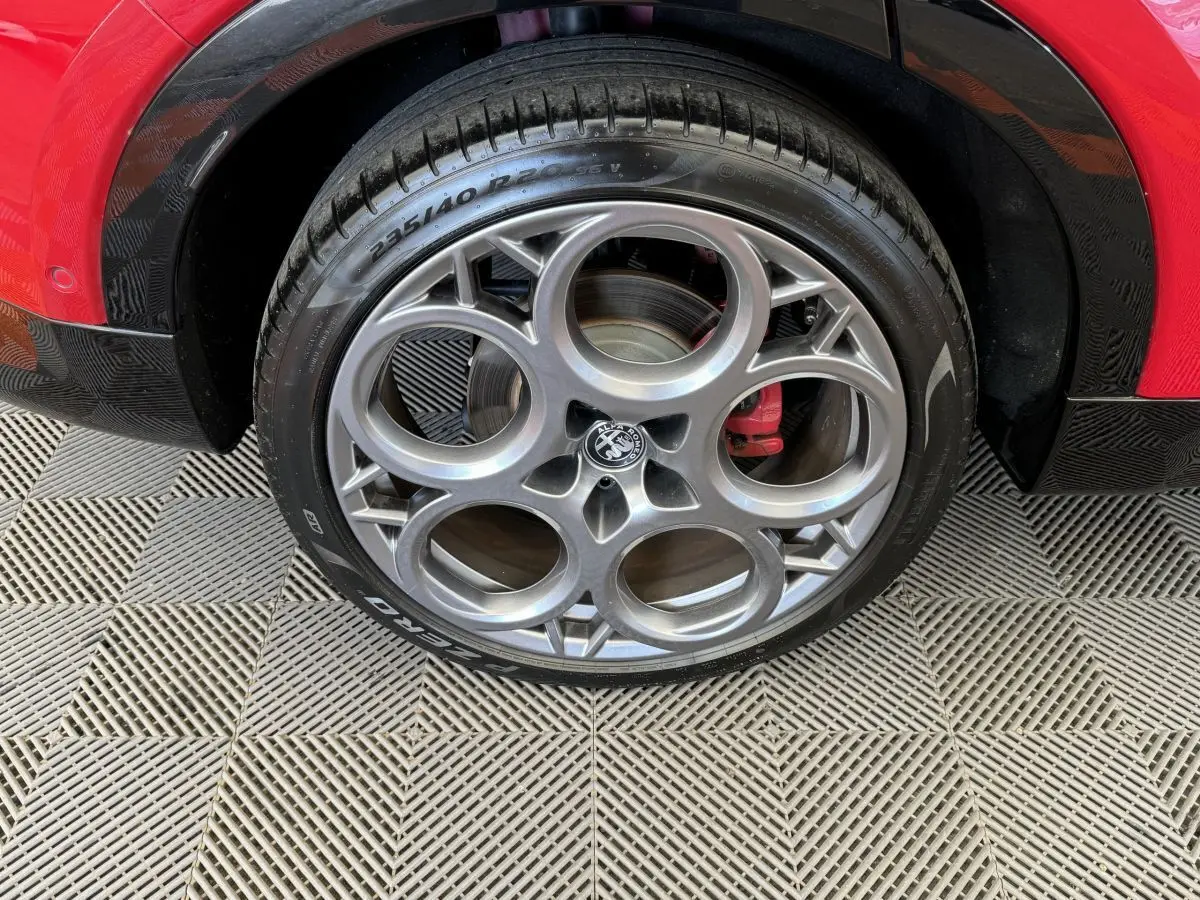 Gros plan sur la roue avant droite rouge d'Alfa Romeo Tonale avec jante en alliage à cercles entrelacés.