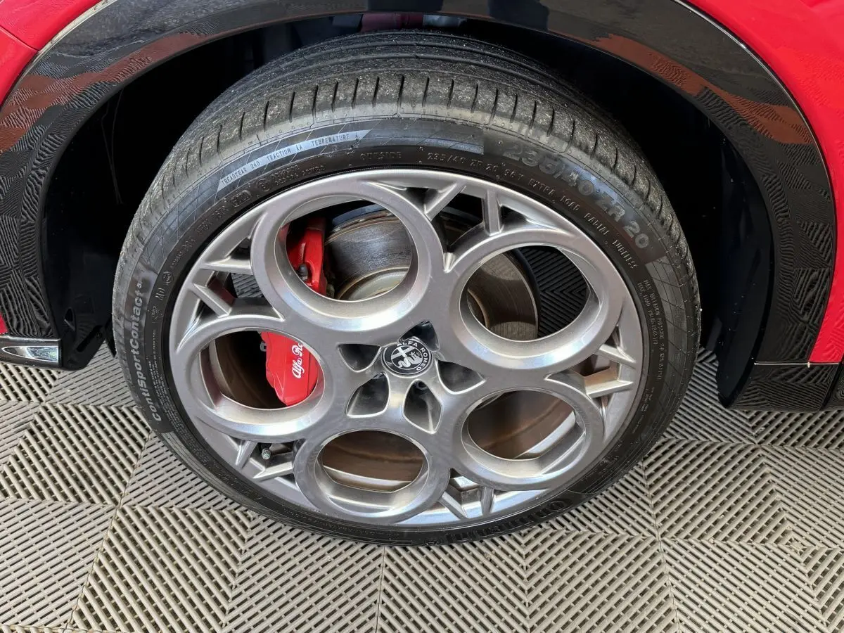 Gros plan sur la roue avant gauche rouge d'un Alfa Romeo Tonale 2023 avec étrier de frein rouge et jante distinctive.