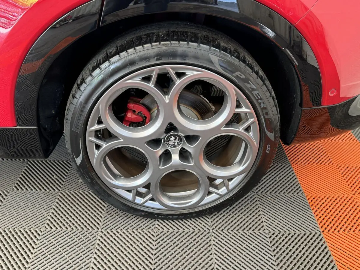 Gros plan sur la roue arrière droite de l'Alfa Romeo Tonale rouge avec jante alu distinctive et pneu Pirelli P Zero.
