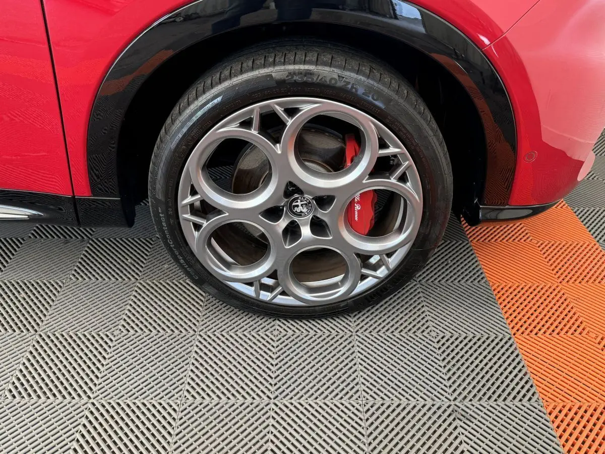 Gros plan sur la roue arrière droite rouge d'une Alfa Romeo Tonale 1.3T PHEV avec jante alu à cinq cercles et étrier rouge visible.