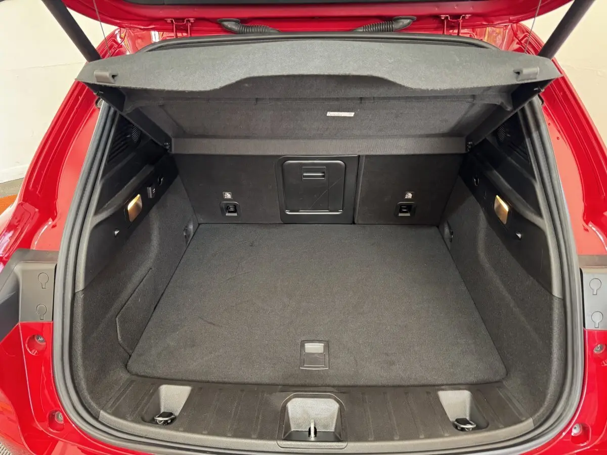 Coffre ouvert vu de l'arrière d'une Alfa Romeo Tonale rouge 2023, espace de chargement propre et éclairé.