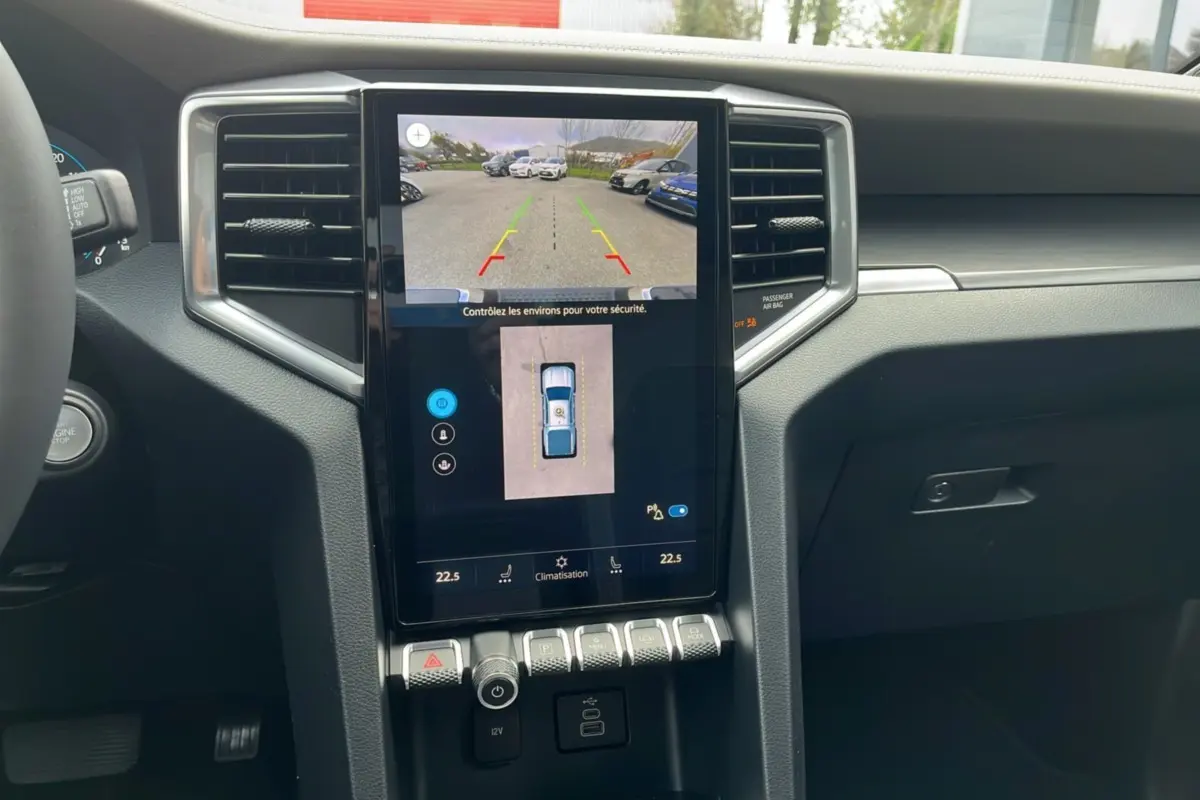 Vue intérieure du tableau de bord du Volkswagen Amarok V6 2025 avec écran tactile affichant la caméra de recul et commandes climatisation.