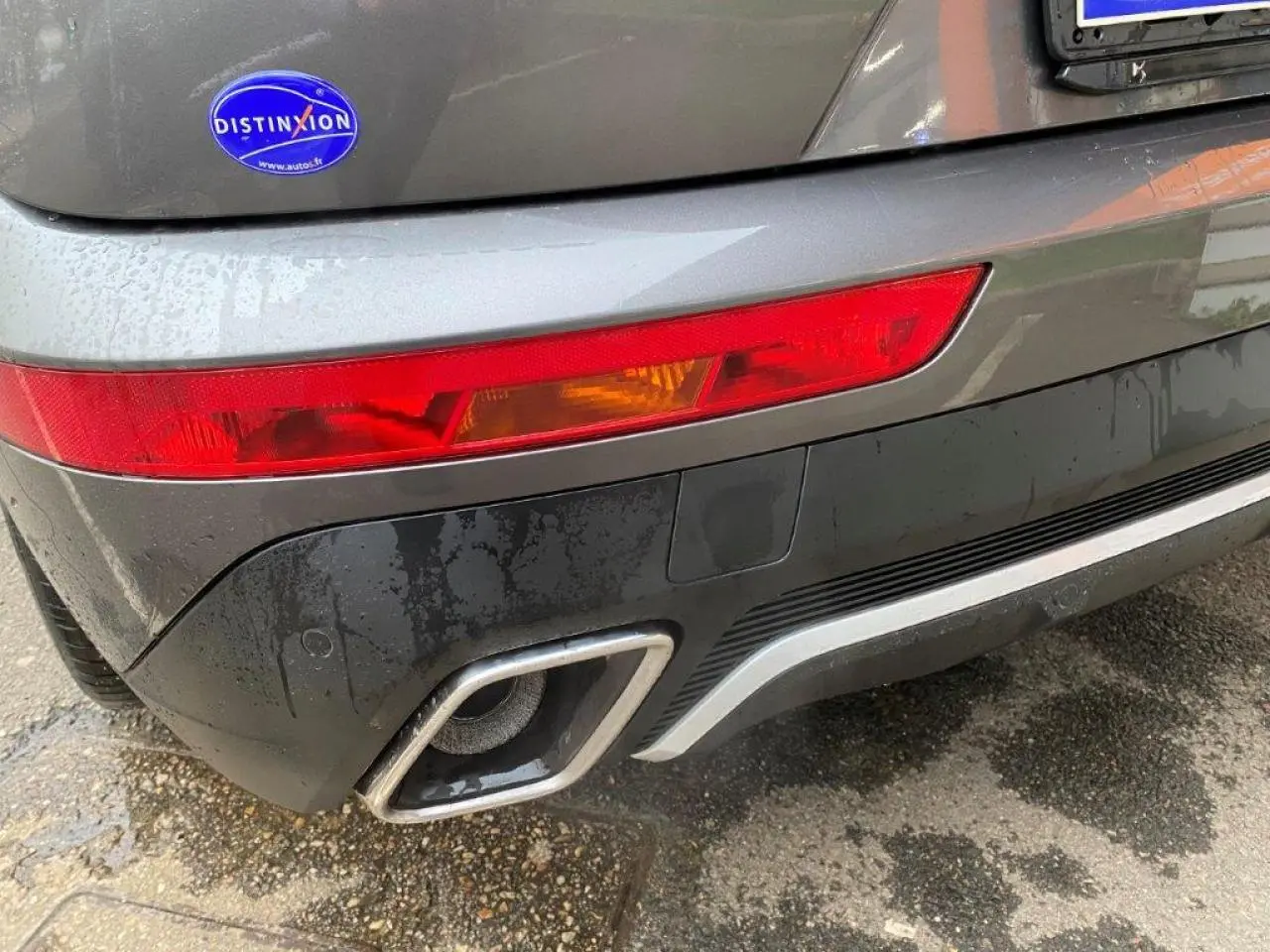 Gros plan sur le feu arrière gauche et la sortie d'échappement chromée d'un DS7 Crossback gris platinium.