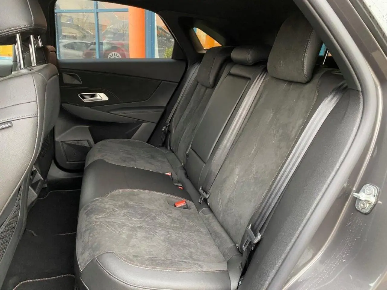 Vue latérale droite de l'intérieur arrière du DS7 Crossback gris platinium, montrant les sièges en cuir et alcantara.