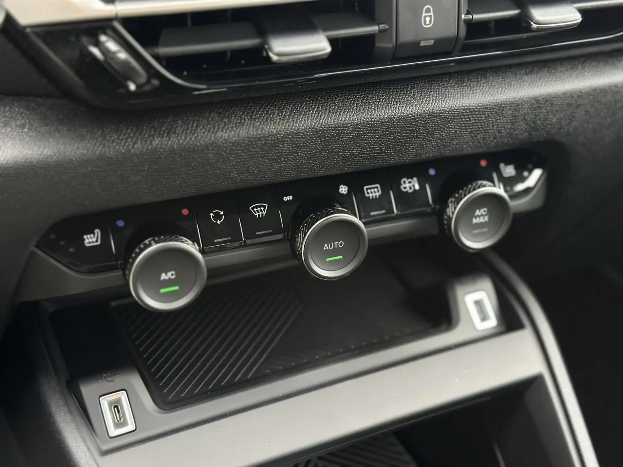 Gros plan sur la console centrale noire du Citroën C4 Manhattan Green 2025, avec commandes climatisation et USB visible.