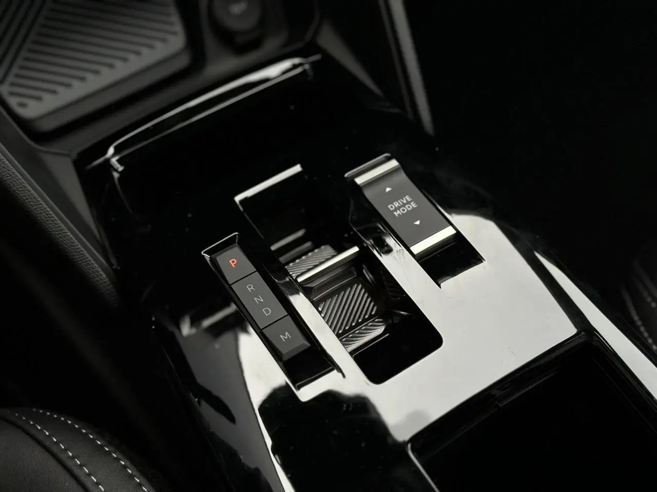 Gros plan sur la console centrale noire brillante du Citroën C4 NV Hybrid 145 e-DSC6 Max avec commandes de boîte auto et mode de conduite.