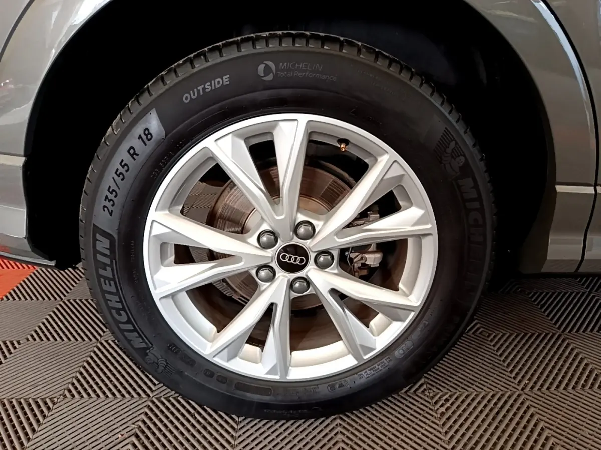 Gros plan sur la roue avant droite d’un Audi Q3 gris foncé, avec jante alliage argent et pneu Michelin.