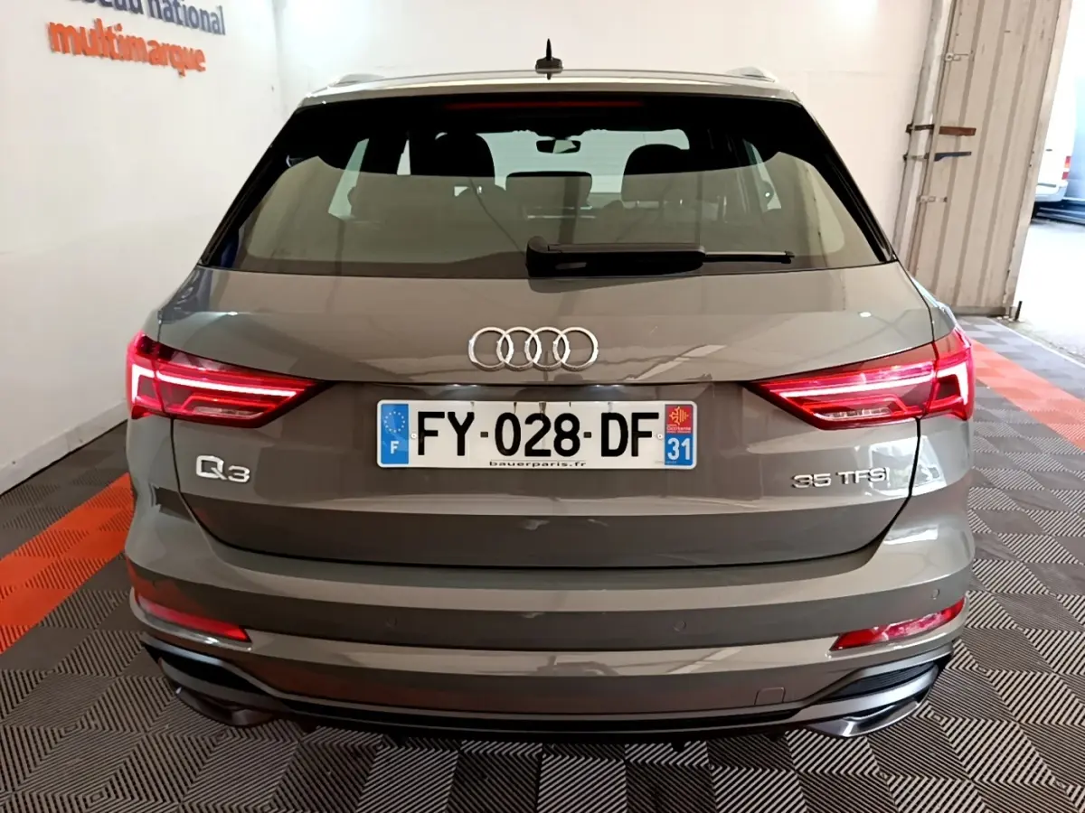 Vue arrière d'un Audi Q3 gris foncé avec feux LED allumés et plaques d'immatriculation françaises visibles.