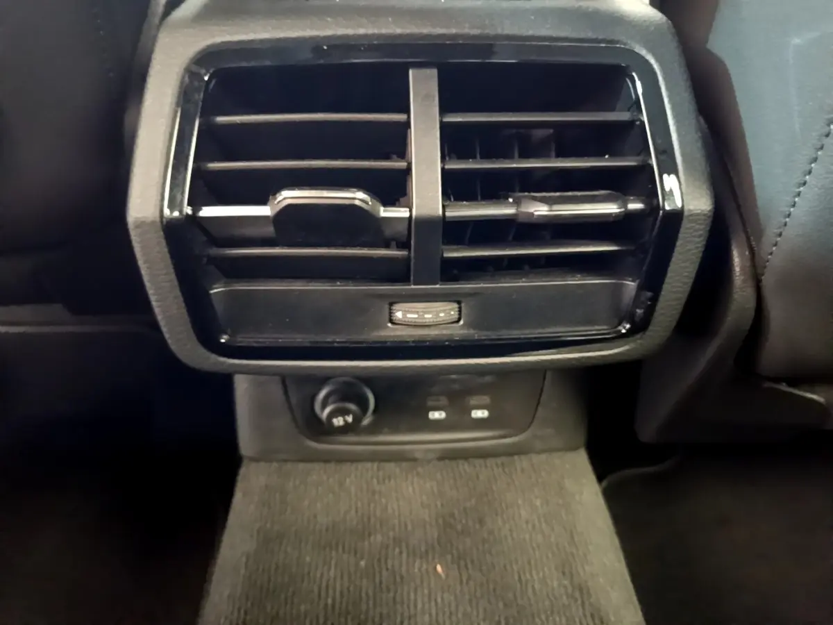 Grille d'aération arrière noire avec prise 12V et ports USB dans l'Audi Q3 gris foncé, vue rapprochée intérieure.