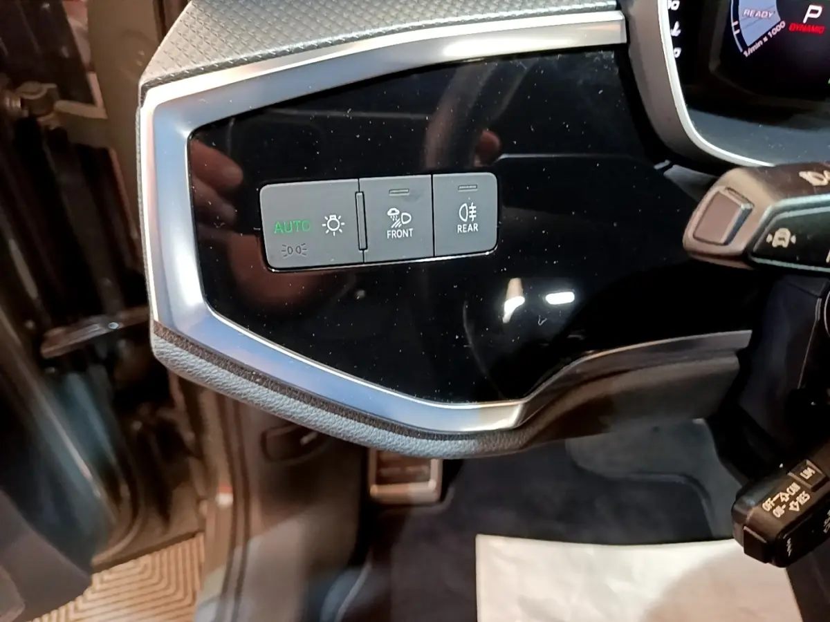 Vue rapprochée des commandes d’éclairage sur le tableau de bord noir brillant de l’Audi Q3 gris foncé.