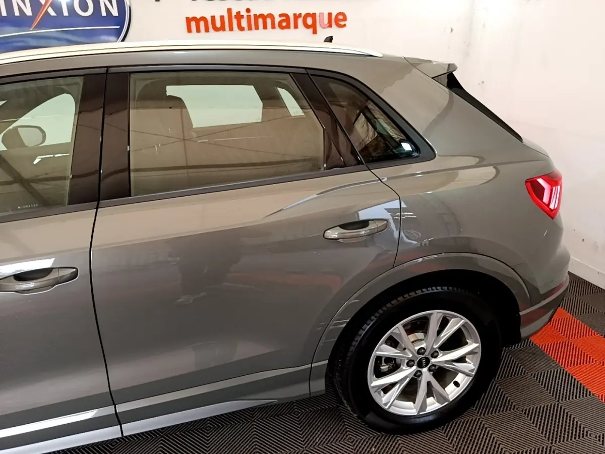 Vue latérale droite sur l'arrière d'un Audi Q3 gris foncé avec jantes alliage et feux arrière LED allumés.