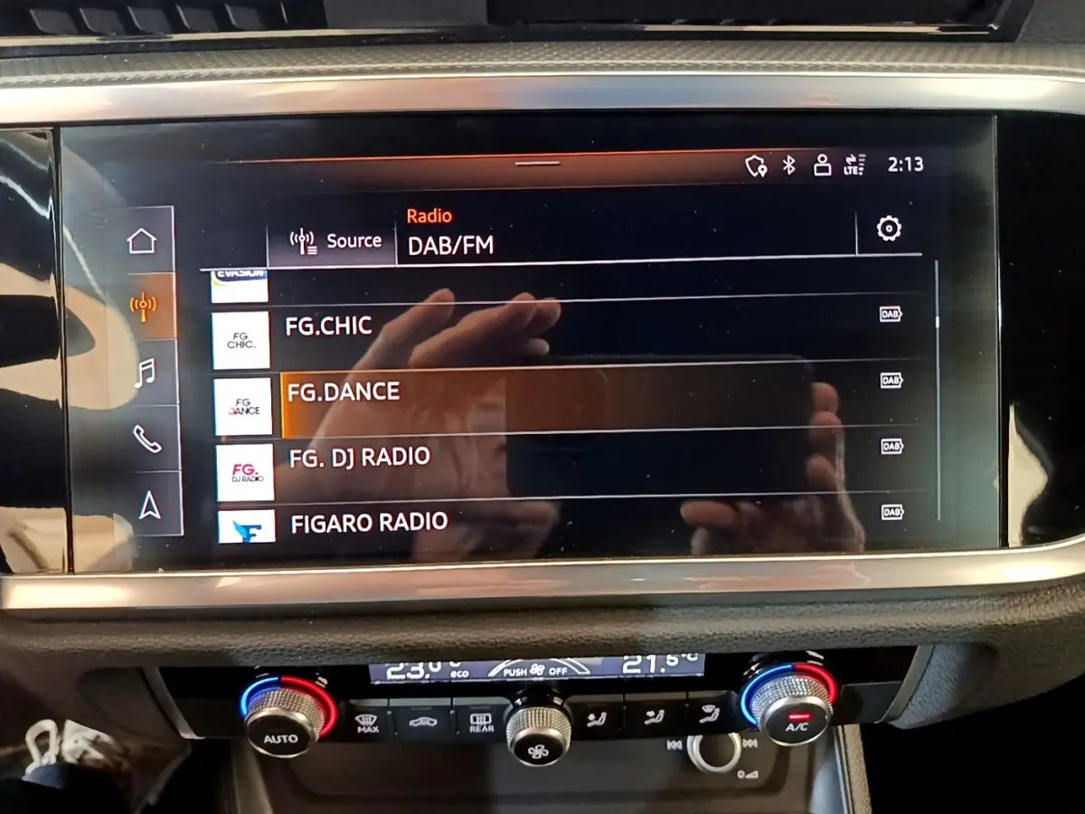 Écran tactile central affichant les stations radio DAB/FM dans l’habitacle d’un Audi Q3 gris foncé.