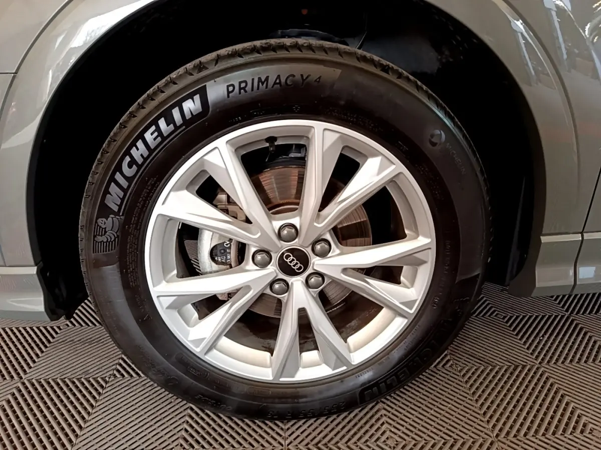 Gros plan sur la roue avant droite d’un Audi Q3 gris foncé, avec jante alliage et pneu Michelin Primacy 4.