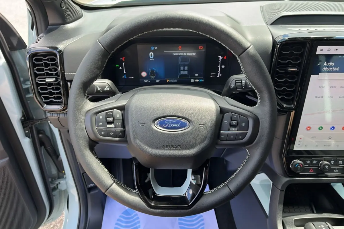 Vue frontale du volant cuir multifonctions noir du Ford Ranger 2.3 PHEV avec tableau de bord numérique et écran tactile.