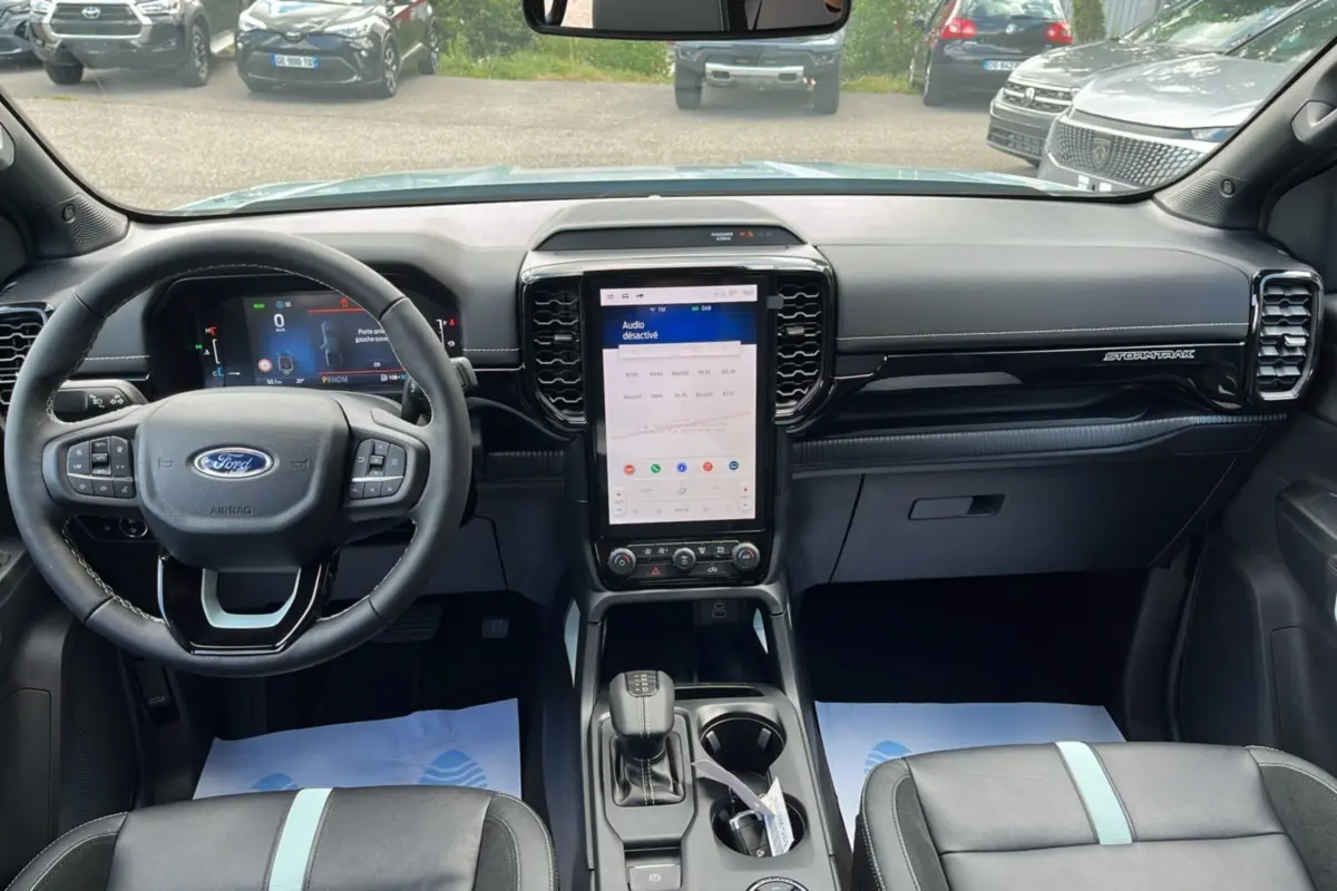 Vue intérieure avant du Ford Ranger gris zen 2026, tableau de bord avec écran tactile vertical et volant multifonctions cuir.