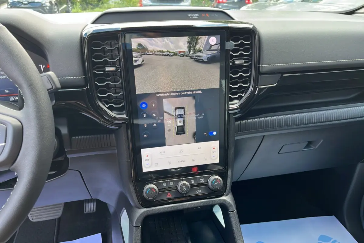 Vue intérieure du tableau de bord du Ford Ranger 2.3 PHEV avec écran tactile vertical affichant la caméra 360° et commandes climatisation.