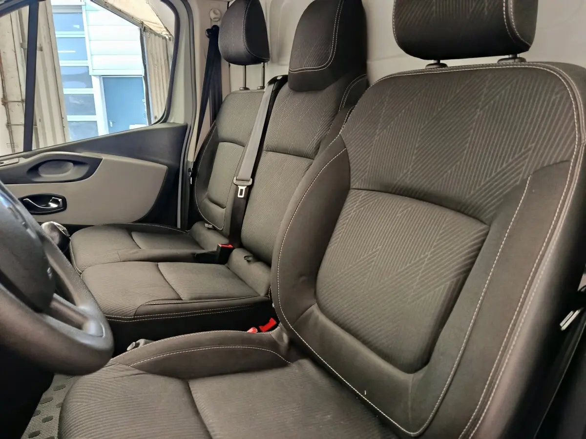 Vue intérieure côté conducteur du Renault Trafic Fourgon 2017, sièges tissu gris foncé avec ceinture de sécurité.