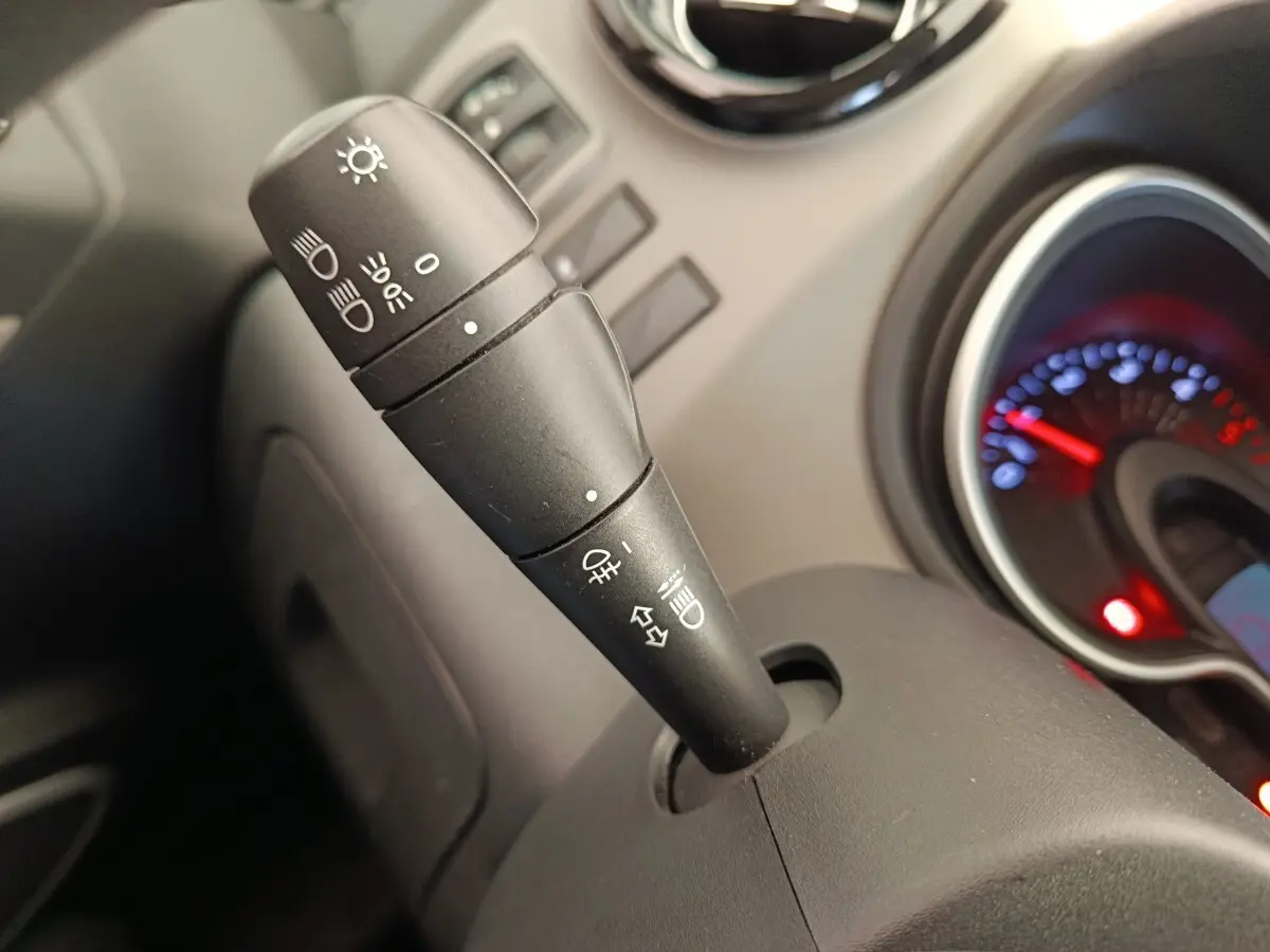 Gros plan sur la commande des phares et clignotants du tableau de bord intérieur du Renault Trafic blanc de 2017.