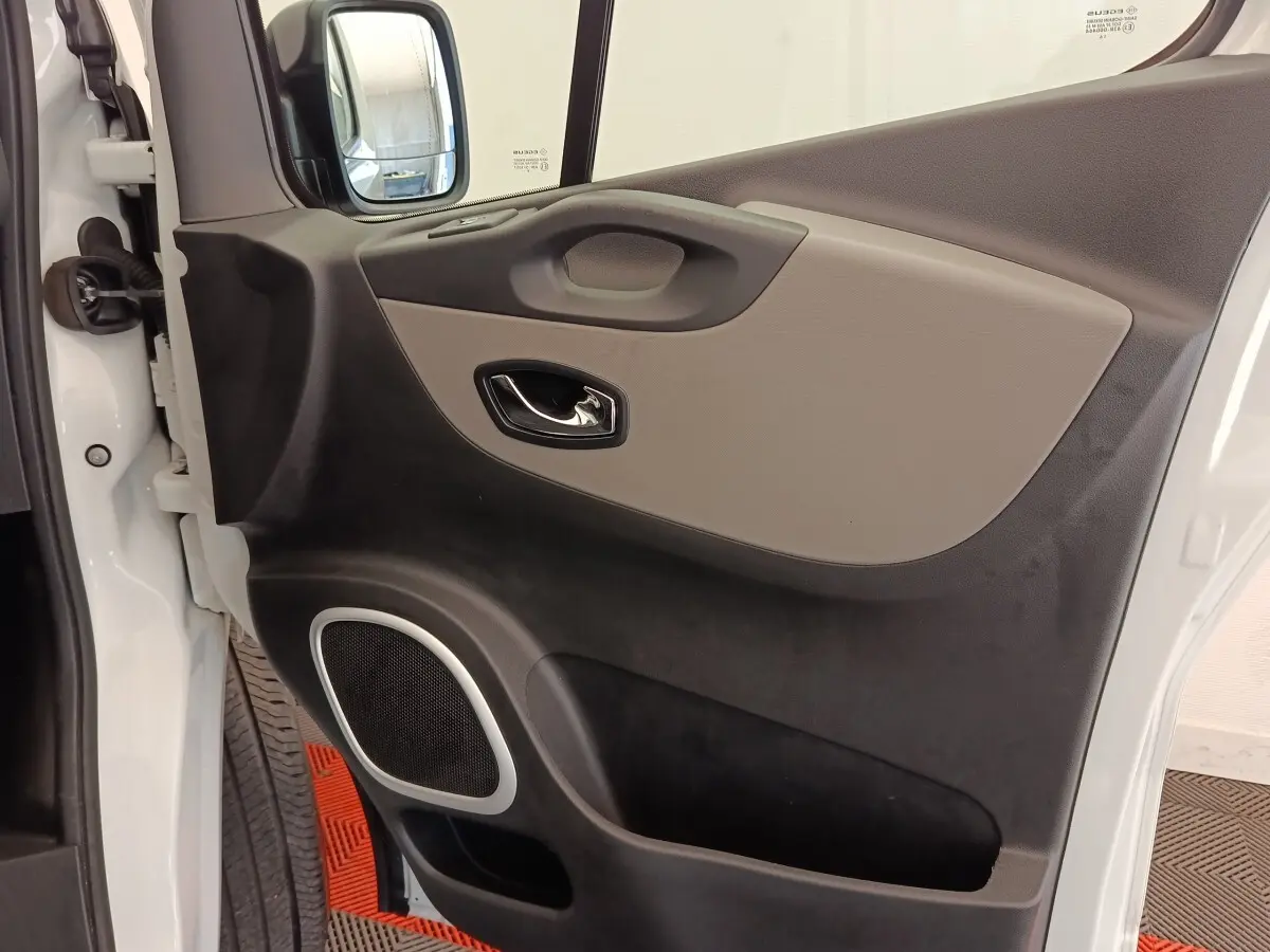 Gros plan sur la porte avant gauche blanche du Renault Trafic Fourgon, avec poignée et haut-parleur intégrés.