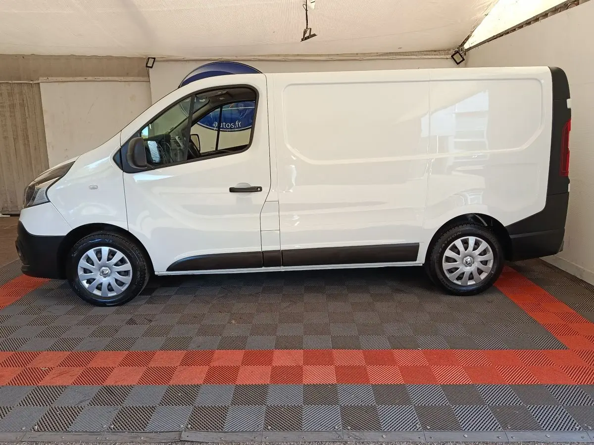 Renault Trafic Fourgon blanc vu de profil côté gauche, avec porte coulissante et jantes acier argentées.
