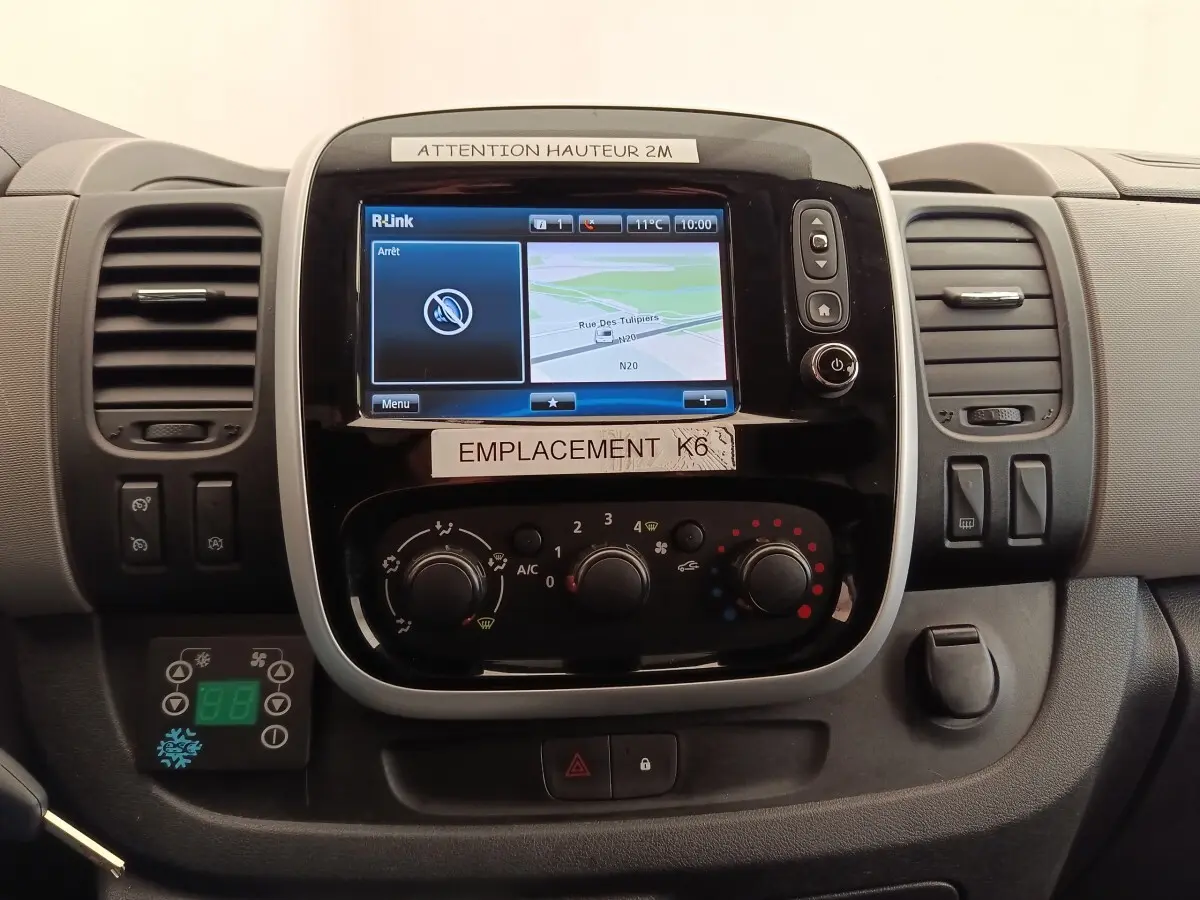 Vue rapprochée du tableau de bord du Renault Trafic blanc, avec écran tactile et commandes de climatisation visibles.