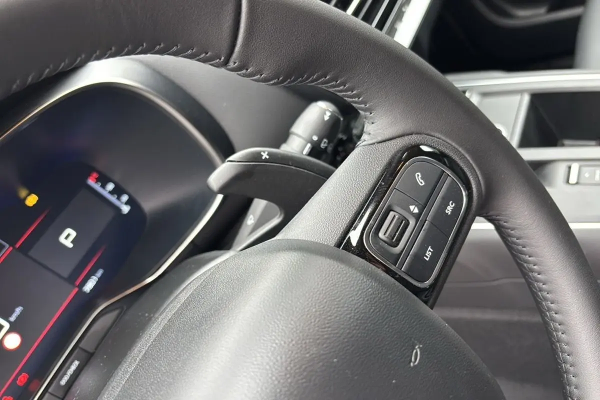 Gros plan sur le volant en cuir noir du Citroën C5 Aircross Hybrid 145, avec commandes intégrées visibles.