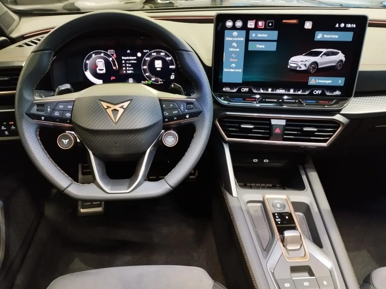 Vue intérieure centrée sur le volant Cupra noir avec logo cuivré et écran tactile HD du tableau de bord.