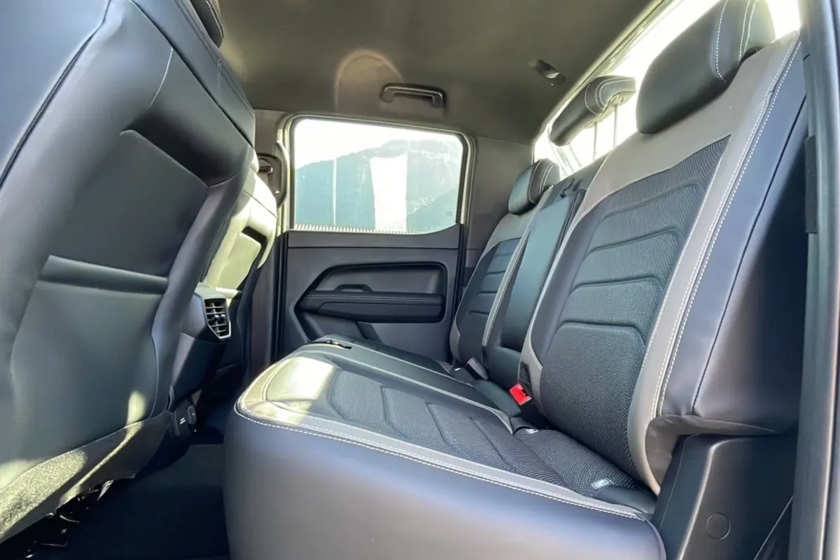 Vue intérieure arrière montrant les sièges noirs en cuir et tissu du Volkswagen Amarok Simple Cabine blanc 2025.