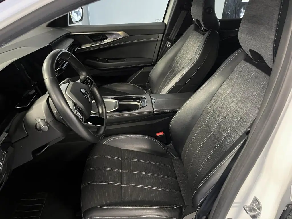 Intérieur avant droit du Renault Austral 2023, sièges mixte simili-cuir gris et volant cuir noir visible.