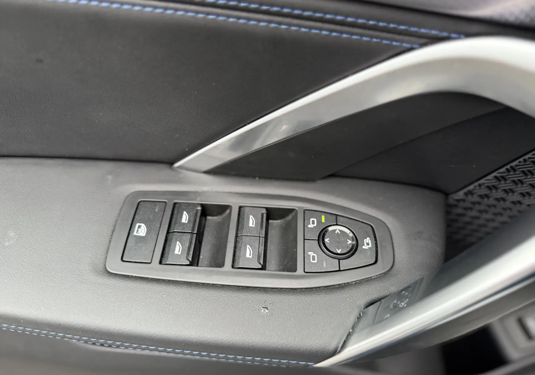 Commandes des vitres et rétroviseurs sur la porte côté gauche d'un BMW X1 blanc Mineral 2025 finition M Sport.