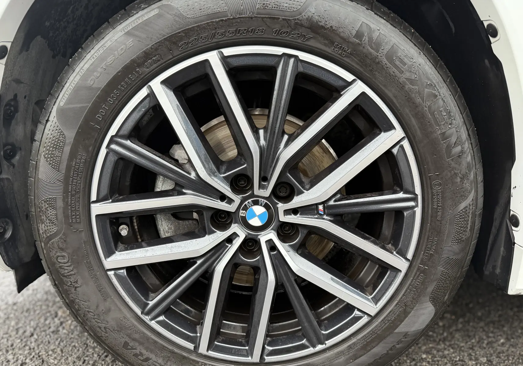 Gros plan sur la jante alliage noire et argentée d'un BMW X1 blanc minéral 2025, mettant en valeur le logo BMW central.