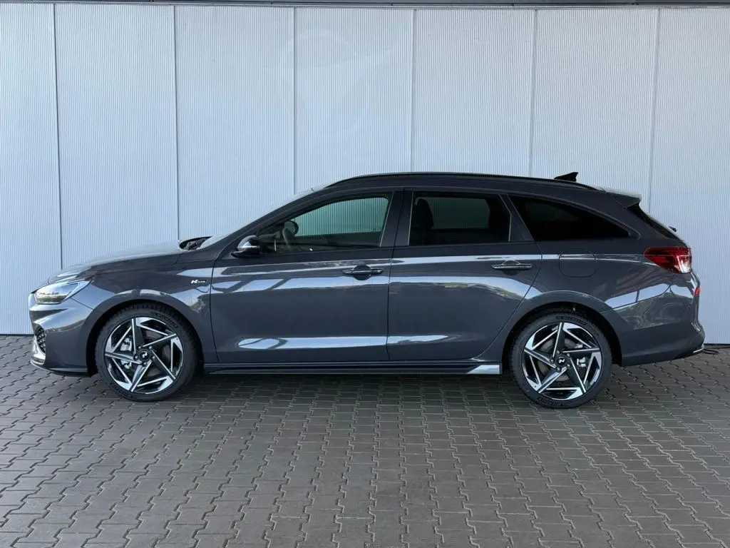 Vue de profil côté gauche d'une Hyundai i30 SW N-LINE gris foncé avec jantes alliage sport et vitres teintées.