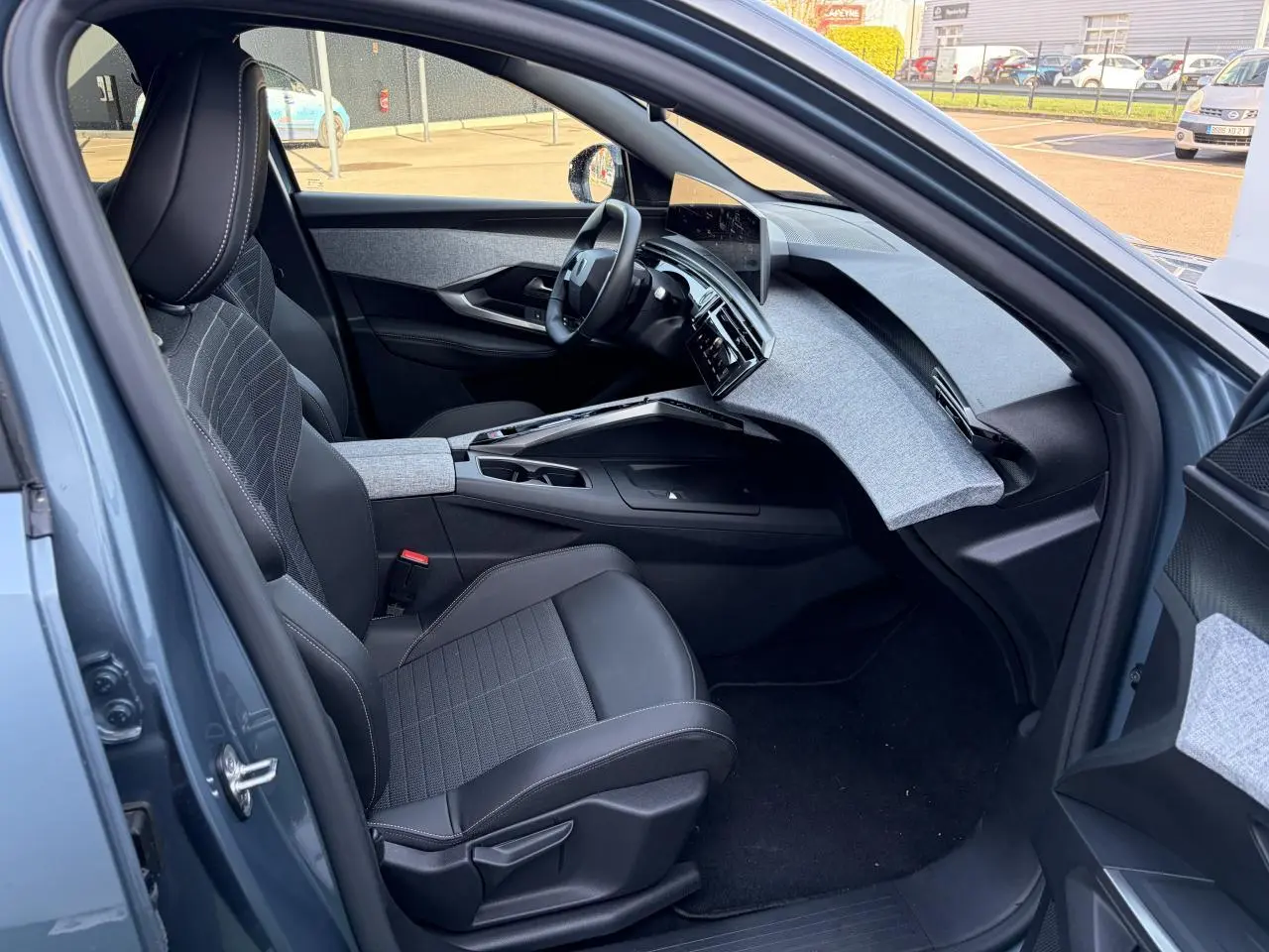 Intérieur côté conducteur du Peugeot 3008 bleu Ingaro, avec tableau de bord tissu gris et écran incurvé flottant.