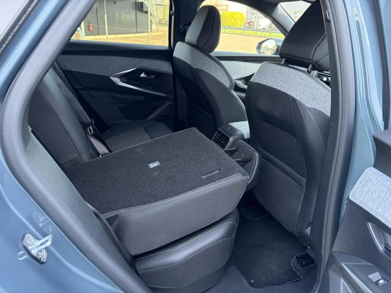 Vue intérieure arrière côté gauche du Peugeot 3008 bleu Ingaro avec dossier de banquette rabattable et sellerie mixte tissu et cuir.