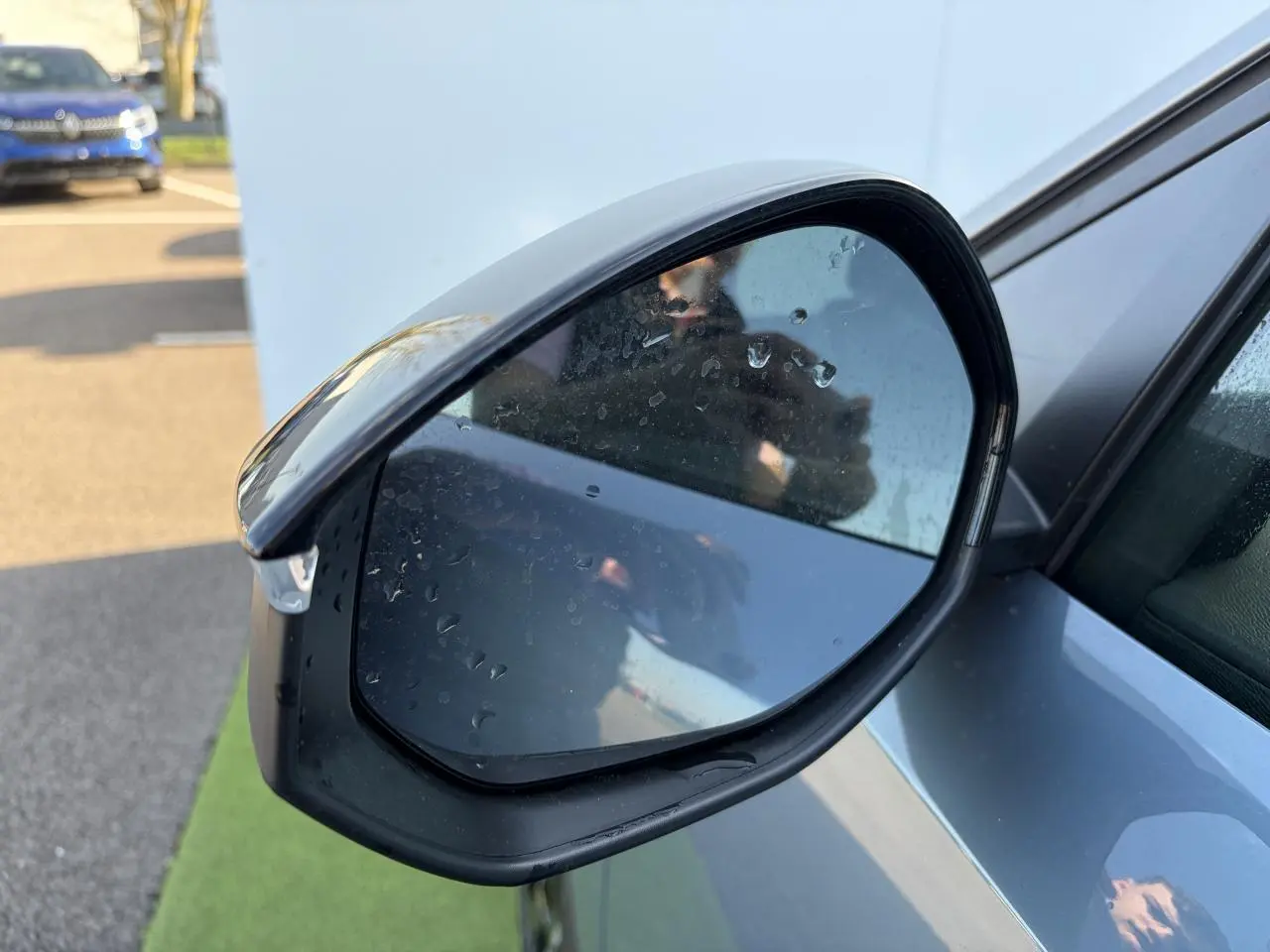 Rétroviseur extérieur droit bleu Ingaro du Peugeot 3008 2024 avec gouttes d'eau et éclairage naturel.