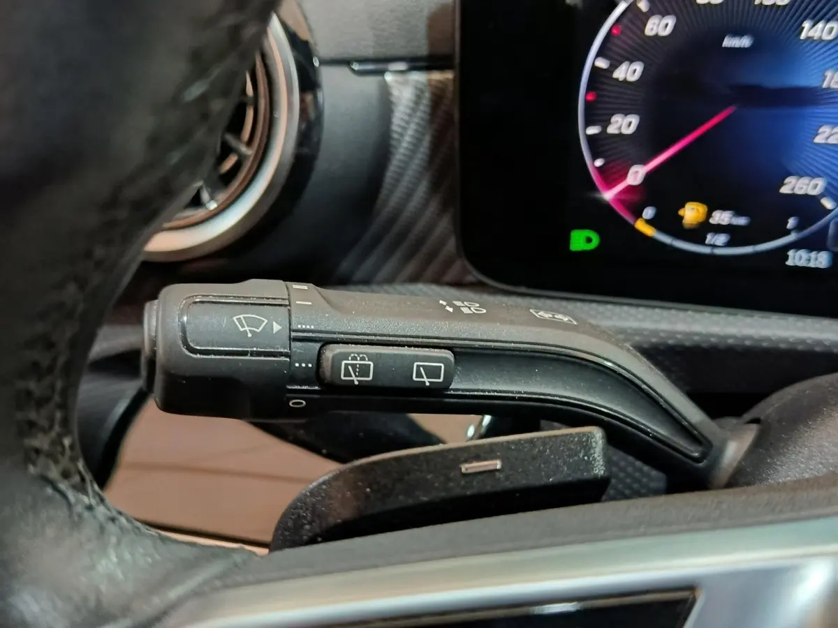 Gros plan sur la manette d’essuie-glace à gauche du volant dans l’habitacle gris foncé du Mercedes GLA 250 e 2023.