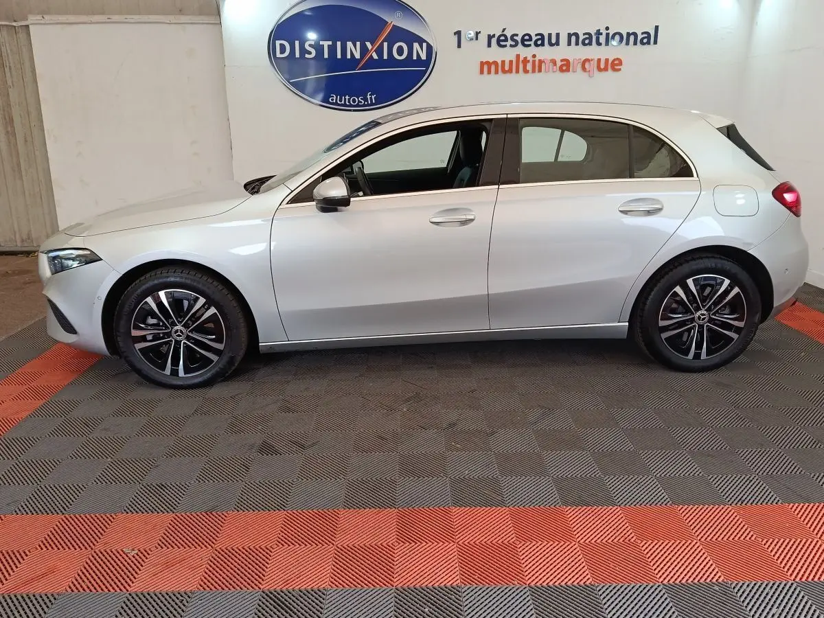 Vue latérale droite d'une Mercedes GLA 250 e Business Line hybride rechargeable gris clair en intérieur showroom.