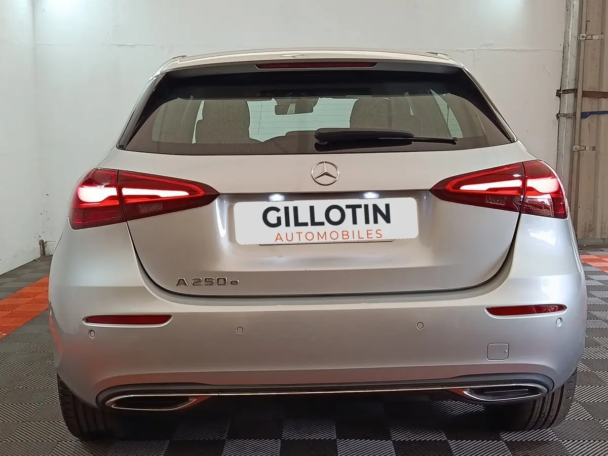 Vue arrière d'une Mercedes GLA 250 e hybride rechargeable gris foncé avec feux LED allumés dans un garage.